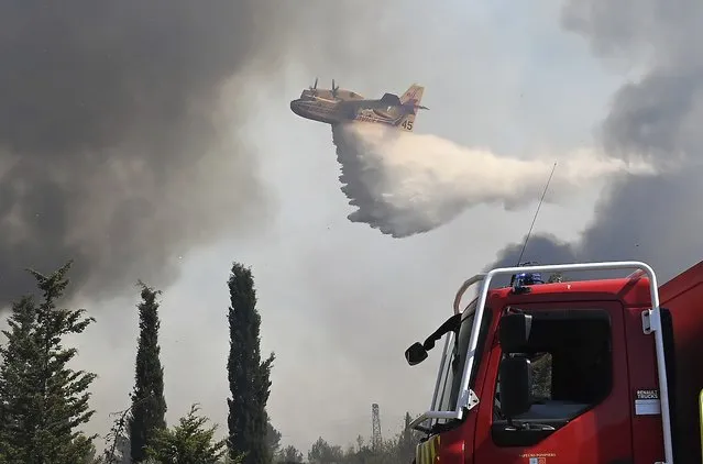 This photo provided by the fire brigade of the Gard region (SDIS 30) shows a water-bombing plane spreads water at a forest fire in Aubais, southern France, July 31, 2022. A weekend wildfire in the southern French Gard region that injured four firefighters has now been contained. Firefighter spokesman Colonel Eric Agrinier told French media that 370 hectares were burned and two homes affected by the flames. (Photo by SDIS 30 service audiovisuel via AP Photo)