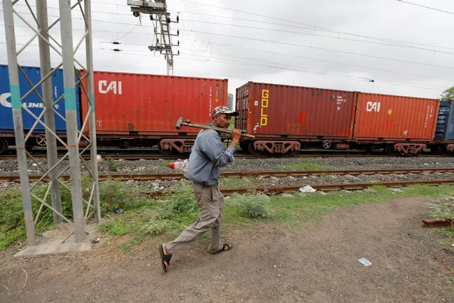 A worker walks past a parked goods train at Khodiyar railway yard in the western state of Gujarat, India, July 11, 2016. (Photo by Amit Dave/Reuters)