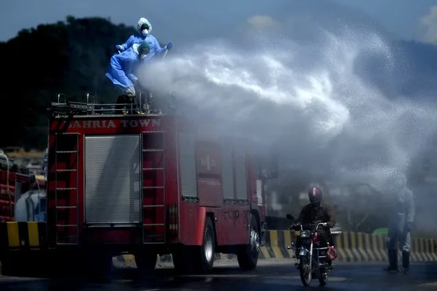 Workers wearing protective gear spray disinfectant on a street at a residential area during a government-imposed nationwide lockdown as a preventive measure against the COVID-19 coronavirus, in Islamabad, Pakistan on March 29, 2020. (Photo by Aamir Qureshi/AFP Photo)