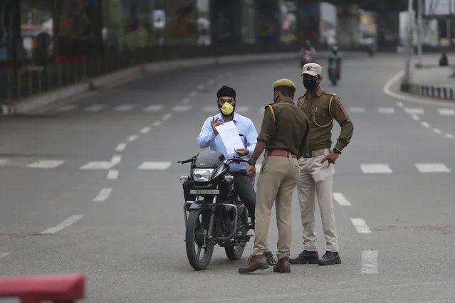 Policemen check papers of a commuter during lockdown in Jammu, India, Wednesday, March 25, 2020. (Photo by Channi Anand/AP Photo)