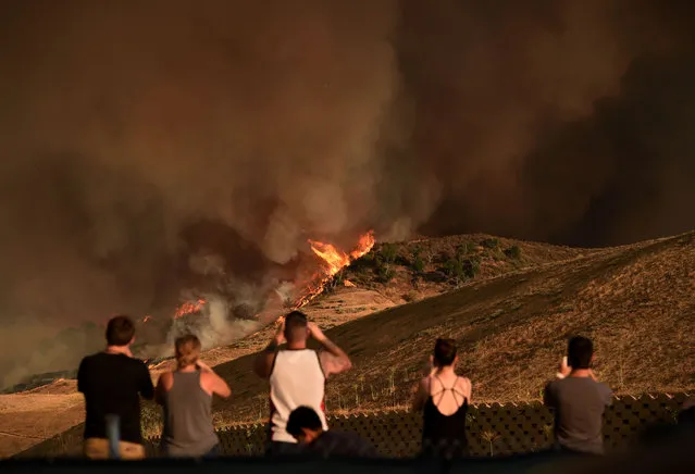 Local residents watch a blaze dubbed the “Sand Fire” as it moves towards Fair Oaks Canyon housing estate in Santa Clarita, California on July 24, 2016. A fire burning out of control in Southern California has grown to a massive 20,000 acres, officials said on July 24, as residents in an area north of Los Angeles were forced to evacuate. (Photo by Mark Ralston/AFP Photo)