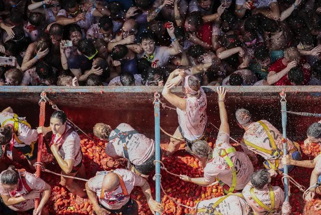 People participate in the traditional and world-wide known tomato fight festival La Tomatina in Bunol (Castellon), eastern Spain, 31 August 2022. As every year on the last Wednesday of August, thousands of people visit the small village of Bunol to attend the Tomatina, a battle in which tons of ripe tomatoes are used to throw at each other. (Photo by Ana Escobar/EPA/EFE)