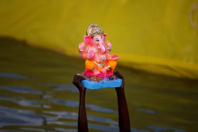 A boy carries an idol of the Hindu god Ganesh, the deity of prosperity, to be immersed in an artificial pond during the Ganesh Chaturthi festival in Ahmedabad, India on September 4, 2022. (Photo by Amit Dave/Reuters)