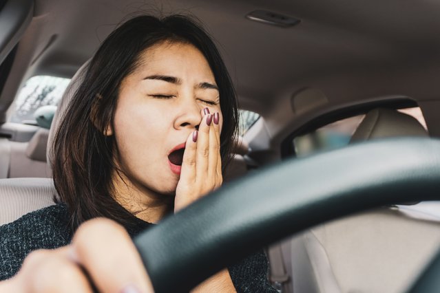 Tired sleepy Asian woman yawning during driving car. (Photo by Doucefleur/Getty Images)