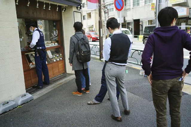 In this April 22, 2020, file photo, people wearing masks to protect themselves against the spread of the new coronavirus queue up to buy lunch at a shop in Tokyo. Under Japan's coronavirus state of emergency, people have been asked to stay home. Many are not. Some still have to commute to their jobs despite risks of infection, while others are dining out, picnicking in parks and crowding into grocery stores with scant regard for social distancing. (Photo by Eugene Hoshiko/AP Photo)