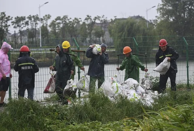 In this photo released by Xinhua News Agency, workers carry sandbags to reinforce a riverbank to prevent the river back flow caused by the approaching typhoon Muifa in Jiashan County of Jiaxing City, east China's Zhejiang Province, Wednesday, September 14, 2022. Typhoon Meihua has weakened to a severe tropical storm Thursday morning, after bringing heavy rains and strong winds to Shanghai and parts of Jiangsu province overnight, according to China's National Meteorological Center. (Photo by Xu Yu/Xinhua via AP Photo)