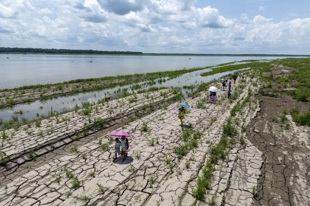 People walk through a part of the Amazon River that shows signs of drought in Santa Sofia, on the outskirts of Leticia, Colombia, October 20, 2024. (Photo by Ivan Valencia/AP Photo)