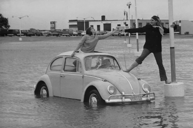 Sally Gomez drives to rescue of friend Michele Moore in flooded parking lot at Hyannis, Mass., September 9, 1969, after torrential rains of Hurricane Gerda flooded low areas of Cape Cod. Ann Davis of Osterville stands up in roof opening to lend a hand. Sally and Michele are from Centerville on the Cape. (Photo by Frank C. Curtin/AP Photo)