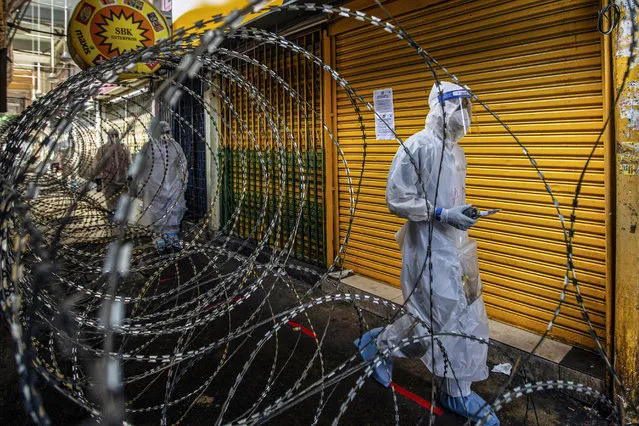 Malaysian health workers wearing protective gear walk inside a locked down area in Kuala Lumpur, Malaysia, 15 May 2020. The area was lock down to conduct COVID-19 screening under the semi-enhanced movement control order (SEMCO) issued by authorities. (Photo by Ahmad Yusni/EPA/EFE/Rex Features/Shutterstock)