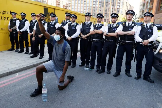 A man wearing a protective face mask kneels in front of police officers during a protest against the death in Minneapolis police custody of African-American man George Floyd near the U.S. Embassy, London, Britain, May 31, 2020. (Photo by John Sibley/Reuters)