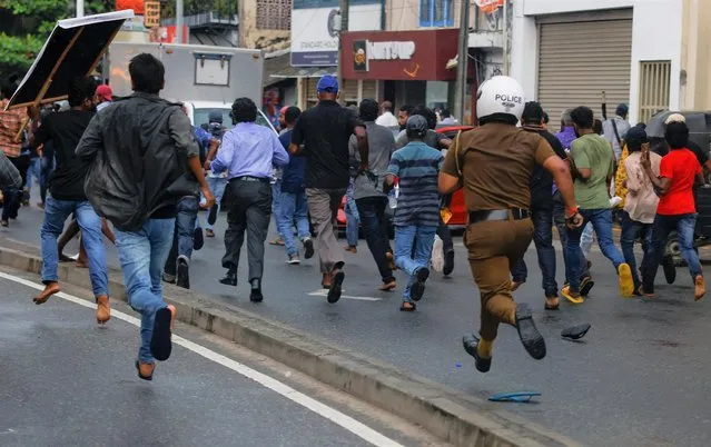 A Sri Lankan police officer chases demonstrators during an anti-government protest by Inter-University Student's Federation, amid the country's economic crisis, in Colombo, Sri Lanka on August 30, 2022. (Photo by Dinuka Liyanawatte/Reuters)