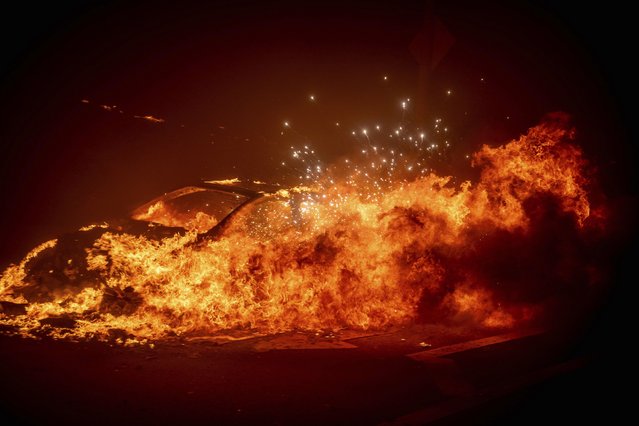 A vehicle burns as the Palisades Fire advances in the Pacific Palisades neighborhood of Los Angeles, Tuesday, January 7, 2025. (Photo by Ethan Swope/AP Photo)
