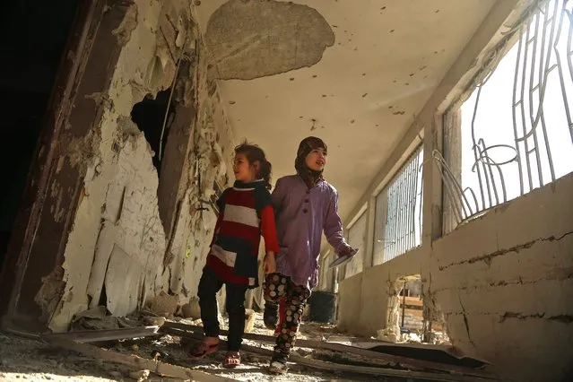 Syrian children tour their damaged school on November 9, 2017 in the besieged rebel-held Eastern Ghouta town of Saqba, on the outskirts of the Syrian capital Damascus, following air raids by government forces on the area the previous day. A “de-escalation zone” deal agreed by regime allies Iran and Russia and rebel backer Turkey has been in place in Eastern Ghouta since July, but it has been repeatedly violated. In addition to an uptick in regime shelling on Eastern Ghouta, humanitarian workers have warned the conditions inside the enclave were increasingly dire. (Photo by Amer Almohibany/AFP Photo)