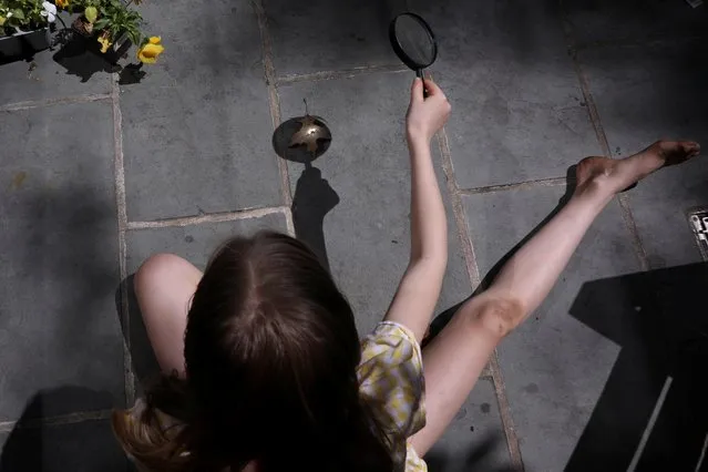 Lydia Hassebroek, 10, uses a magnifying glass to light a leaf on fire in her backyard during the outbreak of the coronavirus disease (COVID-19) in Brooklyn, New York, U.S., May 17, 2020. (Photo by Caitlin Ochs/Reuters)