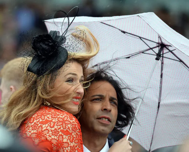 Racegoers shelter from the wind and rain, during day four of the 2016 Yorkshire Ebor Festival, at York Racecourse, in York, England, Saturday August 20, 2016. (Photo by Anna Gowthorpe/PA via AP Photo)