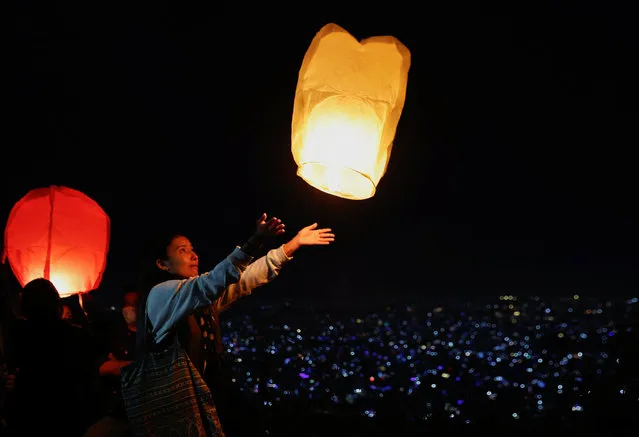 A woman releases a lantern from a hilltop during the Tihar festival, the Hindu festival of lights in Kathmandu, Nepal on October 23, 2022. (Photo by Navesh Chitrakar/Reuters)