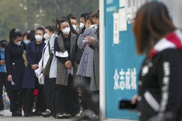 Women wearing face masks wait in line to get their routine COVID-19 throat swab tests at a coronavirus testing site in Beijing, Wednesday, October 26, 2022. (Photo by Andy Wong/AP Photo)