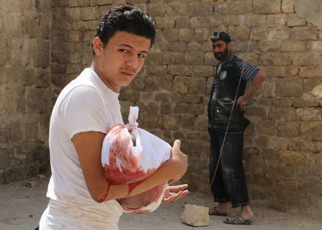 A man carries the body of a dead child after an airstrike in the rebel held Bab al-Nairab neighborhood of Aleppo, Syria, August 25, 2016. (Photo by Abdalrhman Ismail/Reuters)
