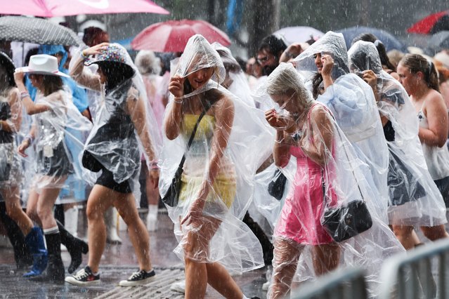 Fans of American singer Taylor Swift, also known as a Swifties, shelter from the rain as they arrive for Swift's concert in Sydney on February 23, 2024. (Photo by David Gray/AFP Photo)