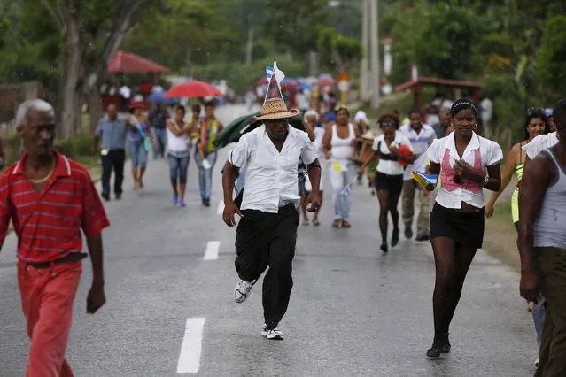 People run from the rain after Pope Francis drove past in El Cobre, Cuba, September 21, 2015. (Photo by Carlos Garcia Rawlins/Reuters)