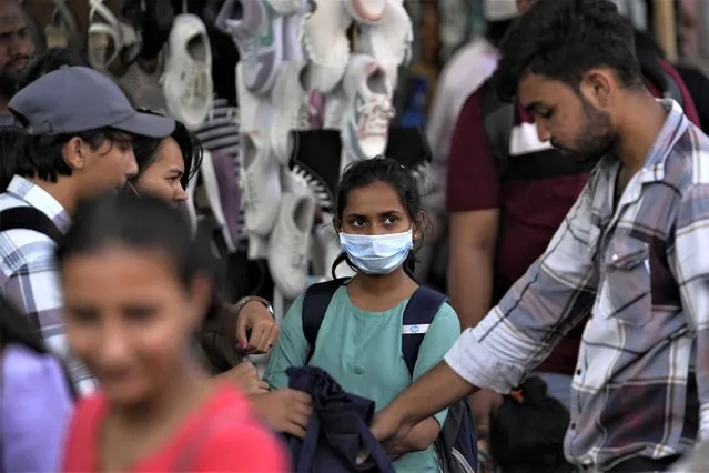 People walk past a girl wearing a face mask in a shopping district of Mumbai, India, Thursday, December 22, 2022. India has begun randomly testing international passengers arriving at its airports for COVID-19, the country’s health minister said Thursday, citing an increase in cases in neighboring China and also asked the public to wear masks and maintain social distancing. (Photo by Rafiq Maqbool/AP Photo)