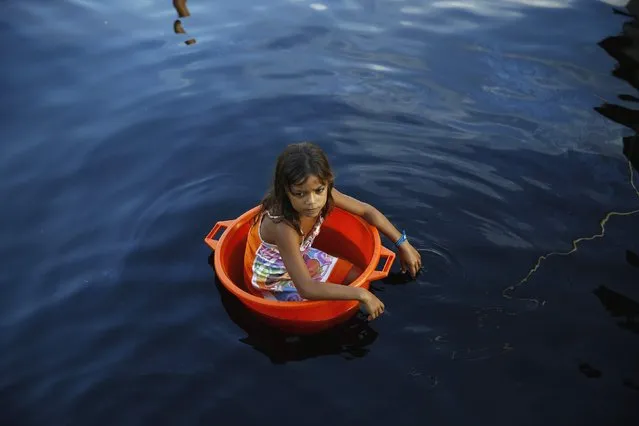 A girl floats in a bucket in the village of Ologa in the western state of Zulia October 23, 2014. (Photo by Jorge Silva/Reuters)
