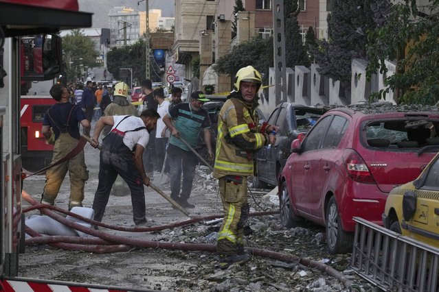 Firefighters and people clean up the scene of an explosion at a residence compound after Israeli attacks in Tehran, Friday, June 13, 2025. (Phoot by Vahid Salemi/AP Photo)