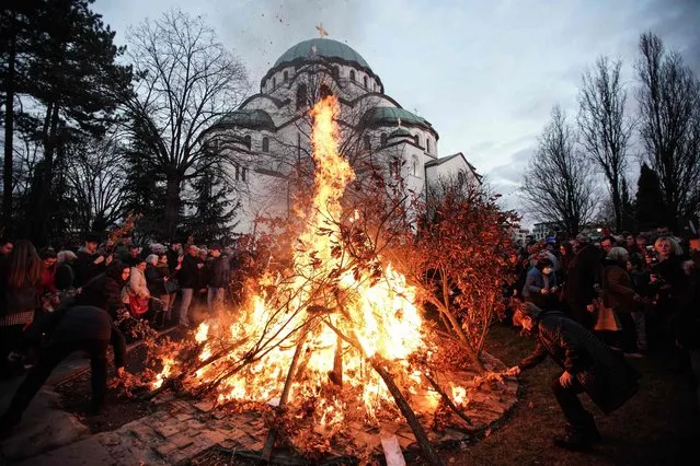 People attend the annual ceremony of bonfire of dried oak branches, the Yule log symbol for the Orthodox Christmas eve according to the Julian calendar, at the Church of Saint Sava in Belgrade on January 6, 2023. (Photo by Oliver Bunic/AFP Photo)