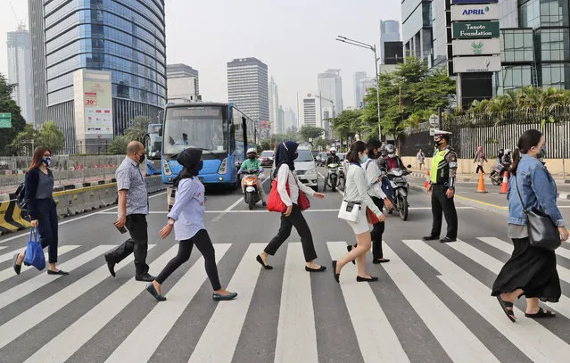 People, wearing a face mask as a precaution against the new coronavirus outbreak, walk on a pedestrian crossing at the main business district in Jakarta, Indonesia, Monday, September 14, 2020. (Photo by Tatan Syuflana/AP Photo)