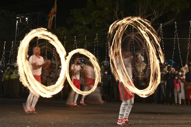 In this photograph taken on August 22, 2020, Sri Lanka's traditional fire dancers perform in front of the Bellanwila Temple as they take part in a procession during the Esala Perahera festival in Colombo. Esala Perahera festival, which usually draws thousands of spectators every year, took place with no spectator insight due to the restrictions amid COVID-19 coronavirus pandemic. (Photo by Lakruwan Wanniarachchi/AFP)