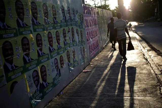 People walk next to electoral posters plastered on a wall in a street of Port-au-Prince, Haiti, September 26, 2016. (Photo by Andres Martinez Casares/Reuters)