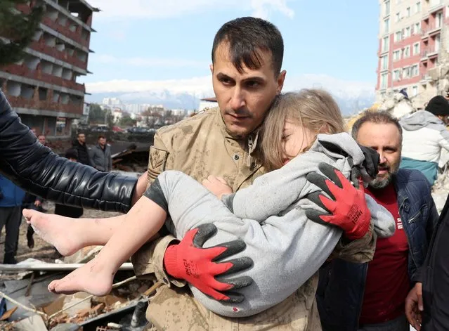 Muhammet Ruzgar, 5, is carried out by a rescuer from the site of a damaged building, following an earthquake in Hatay, Turkey on February 7, 2023. (Photo by Umit Bektas/Reuters)