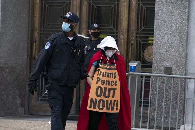 Demonstrators opposed to the confirmation of President Donald Trump's Supreme Court nominee, Judge Amy Coney Barrett, dressed as characters from “The Handmaid's Tale”, are arrested after blocking an entrance of the Dirksen Senate office building, Thursday, October 22, 2020, on Capitol Hill in Washington. (Photo by Jose Luis Magana/AP Photo)