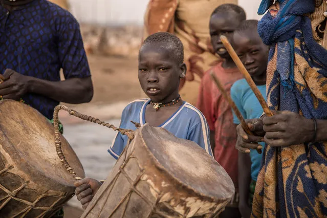 Sudanese boys from Dinka tribe hold instruments during their church' s prayer in the early morning at their cattle camp in Mingkaman, Lakes State, South Sudan on March 4, 2018. (Photo by  Stefanie Glinski/AFP Photo)