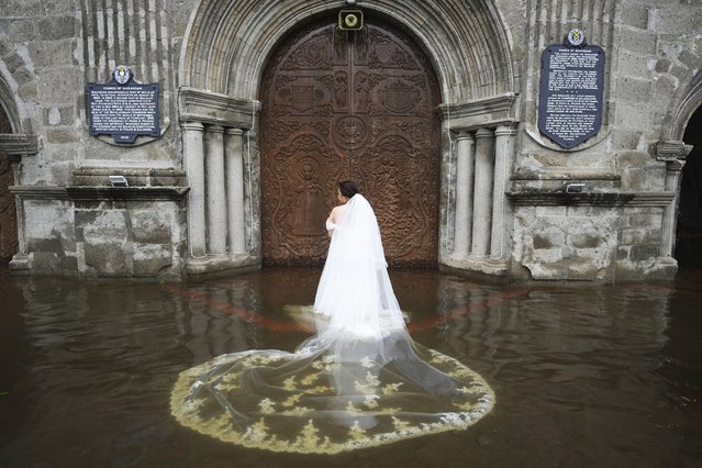 Bride Jamaica Aguilar prepares to enter the flooded Barasoain church for her wedding in Malolos, Bulacan province, Philippines on Tuesday, July 22, 2025. (Photo by Aaron Favila/AP Photo)
