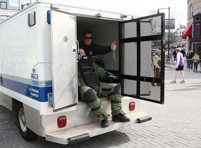 Members of the bomb squad prepare investigate a suspicious item on the road as runners pass near Kenmore Square after two bombs exploded during the 117th Boston Marathon on April 15, 2013 in Boston, Massachusetts. (Photo by Alex Trautwig)