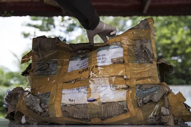 A policeman opens a box with personal possessions of 2004 tsunami victims to be photographed outside a police station in Takua Pa, in Phang Nga province December 19, 2014. (Photo by Damir Sagolj/Reuters)