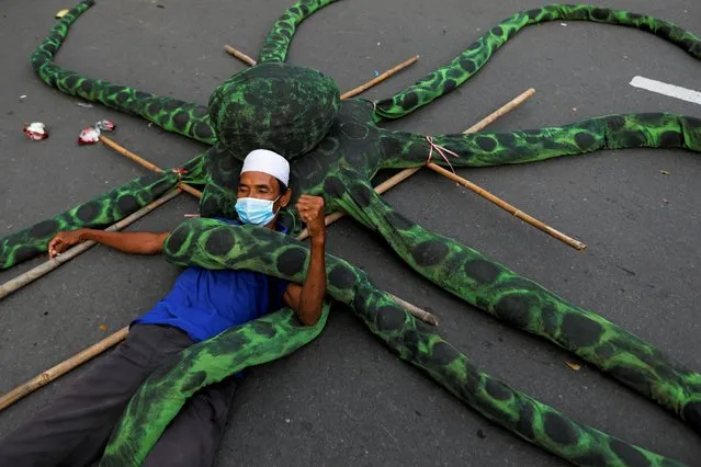 A fisherman wearing a protective mask lies on an artificial octopus during a protest against the government's labor reforms in a “job creation” bill in Jakarta, Indonesia, November 10, 2020. (Photo by Willy Kurniawan/Reuters)