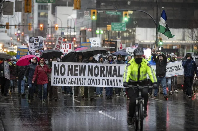 People opposed to COVID-19 health guidelines march with a police escort in downtown Vancouver, British Columbia, Sunday, December 13, 2020. (Photo by Darryl Dyck/The Canadian Press via AP Photo)