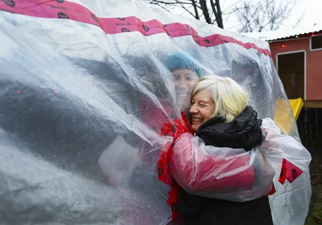 Carolyn Ellis, left, creator of the hug glove hugs her mother Susan Watts, 74, in her backyard on Christmas Eve during the COVID-19 pandemic in Guelph, Ont., Thursday, December 24, 2020. Watts is a retired nurse who lives in an apartment near by and gets to come over outside and hug her daughter's family. (Photo by Nathan Denette/The Canadian Press via AP Photo)