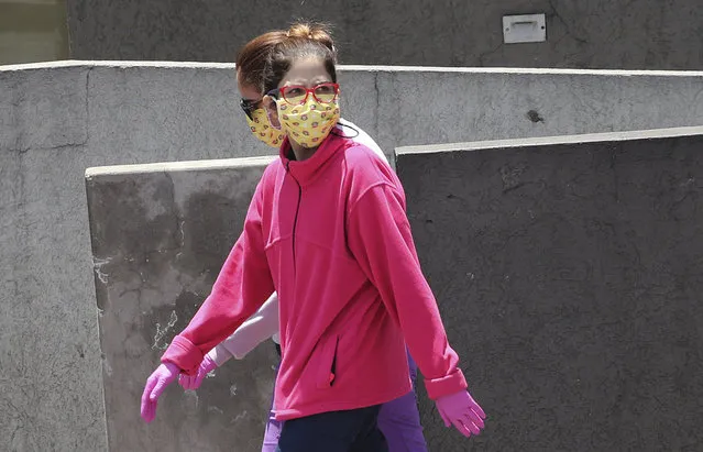 Women wear face masks and gloves as a precaution against the spread of the new coronavirus, in Quito, Ecuador, Thursday, March 19, 2020. The government has declared a “health emergency”, restricting movement to only those who provide basic services, enacting a curfew, and closing schools. (Photo by Dolores Ochoa/AP Photo)