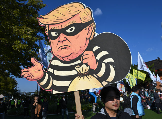 A South Korean protester holds a placard showing a caricature of Trump depicted as a thief during a rally against US President Trump's visit to attend the Asia-Pacific Economic Cooperation (APEC) Summit, in Gyeongju on October 29, 2025. (Photo by Jung Yeon-je/AFP Photo)