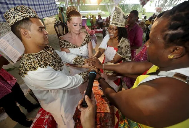 Dutch migrants Reggio de Jong (L) and Elisabeth Cobben (2nd L) hold hands as they are wedded by priest Dorenia Babel (C) in the second public marriage ever held under the African-American Winti religion in district Para, Suriname, November 18, 2015. (Photo by Ranu Abhelakh/Reuters)