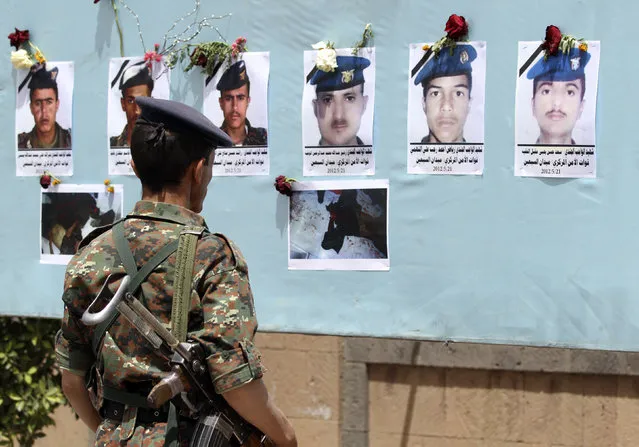 A soldier looks at portraits of victims of a suicide attack, during a protest to condemn the attack that killed more than 90 soldiers, in Sanaa May 29, 2012. (Photo by Mohamed al-Sayaghi/Reuters)