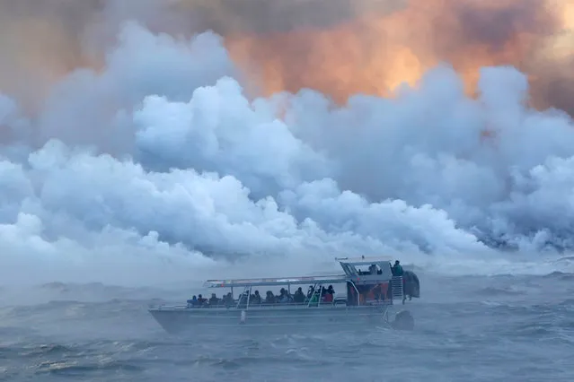People watch from a tour boat as lava flows into the Pacific Ocean in the Kapoho area, east of Pahoa, during ongoing eruptions of the Kilauea Volcano in Hawaii, U.S., June 4, 2018. (Photo by Terray Sylvester/Reuters)