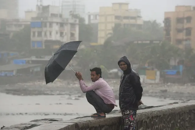 Indians look on by the sea front during heavy rain showers in Mumbai on June 18, 2013. The monsoon, which India's farming sector depends on, covers the subcontinent from June to September, usually bringing some flooding. But the heavy rains arrived early this year, catching many by surprise. The country has received 68 percent more rain than normal for this time of year, data from the India Meteorological Department shows. (Photo by Punit Paranjpe/AFP Photo)