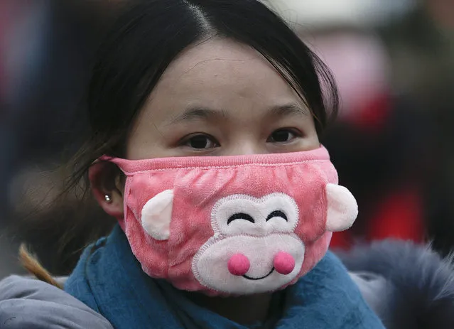 In this December 8, 2015 photo, a woman wears a mask to protect herself from pollutants near the Forbidden City on a heavily polluted day in Beijing. (Photo by Andy Wong/AP Photo)