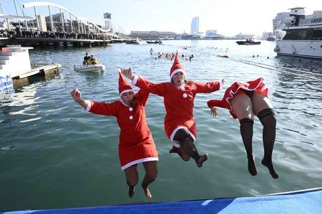 Participants in Santa costumes jump into the water during the 115th edition of the Copa Nadal (Christmas Cup) swimming race in Barcelona's Port Vell on December 25, 2024. The traditional 200-meter Christmas swimming race gathered more than 450 participants on Barcelona's Port Vell. (Photo by Josep Lago/AFP Photo)