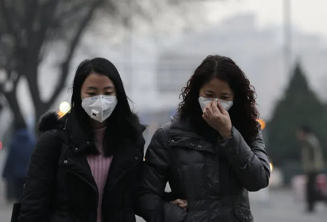 Women wear masks for protection against the pollution as they walk along a street on a polluted day in Beijing, Sunday, December 13, 2015. China's push for a global climate pact is partly because of its own increasingly pressing need to solve serious environmental problems, observers said Sunday. (Photo by Andy Wong/AP Photo)