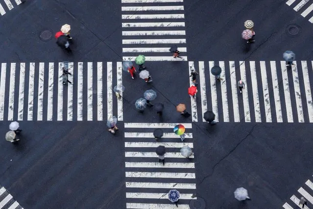 Pedestrians cross an intersection in the rain in the Ginza district of Tokyo on May 23, 2023. (Photo by Richard A. Brooks/AFP Photo)